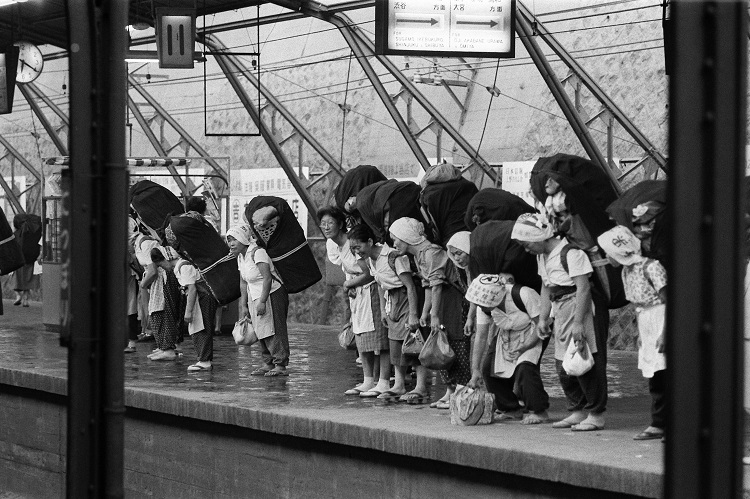 1960年代の東京・日暮里駅。大きな荷物を背負って電車を待つ「かつぎやさん（行商の女性）」たち（時事通信フォト）