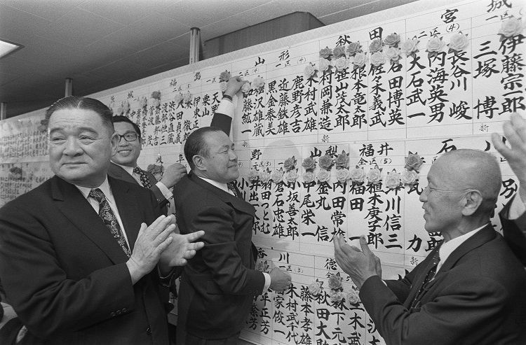1972年総選挙で当選者の名前の上にバラの花を着ける自民党の田中角栄総裁(中央)(時事通信フォト)